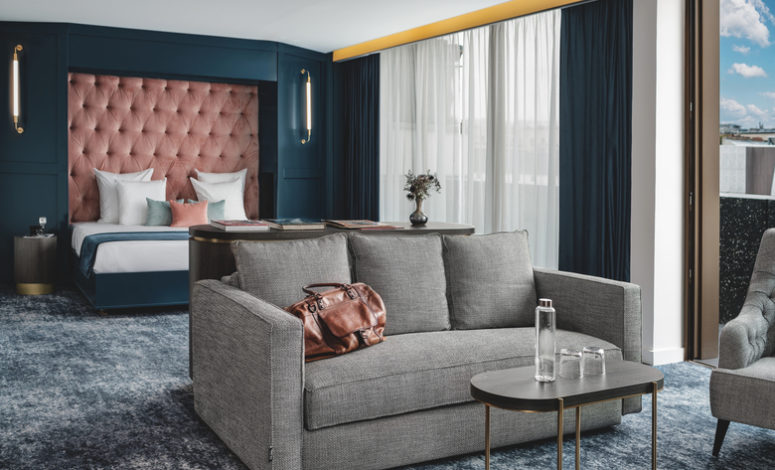 Vue du lit et de l’espace salon d’une chambre moderne et décorée dans un lieu pour séminaire Paris