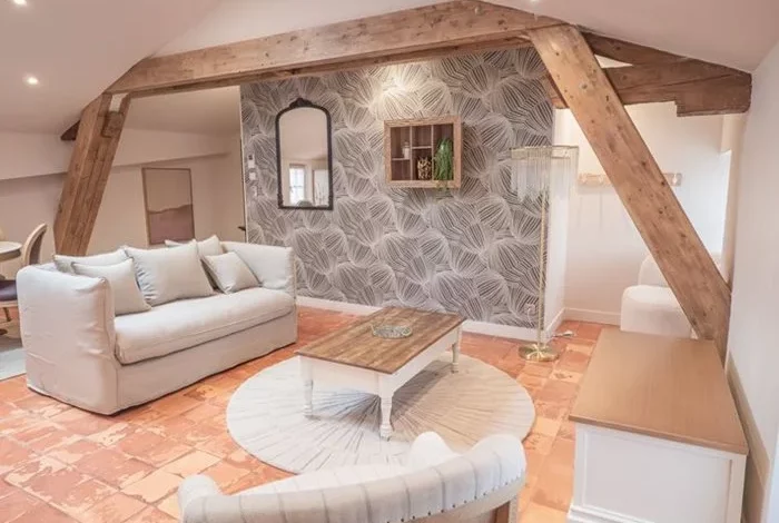 Salon cosy avec cheminée en pierre et poutres apparentes