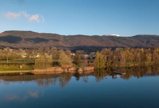 Vue sur un lac entouré d’arbres et de montagnes, pour un séminaire au vert près de Genève et d’Annecy