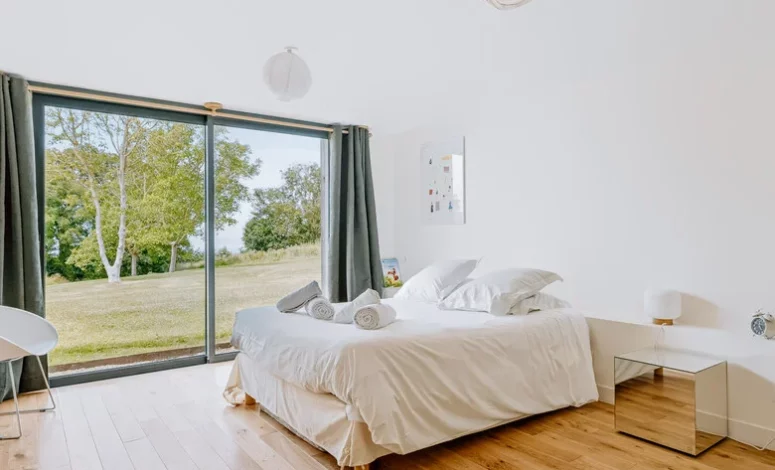 Chambre lumineuse avec lit double et vue sur le jardin normand