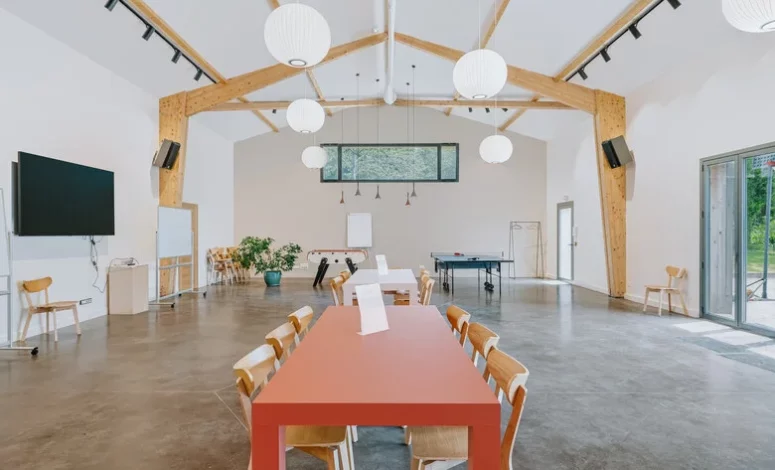 Salle de réunion avec grande table en bois et charpente apparente pour un séminaire au vert
